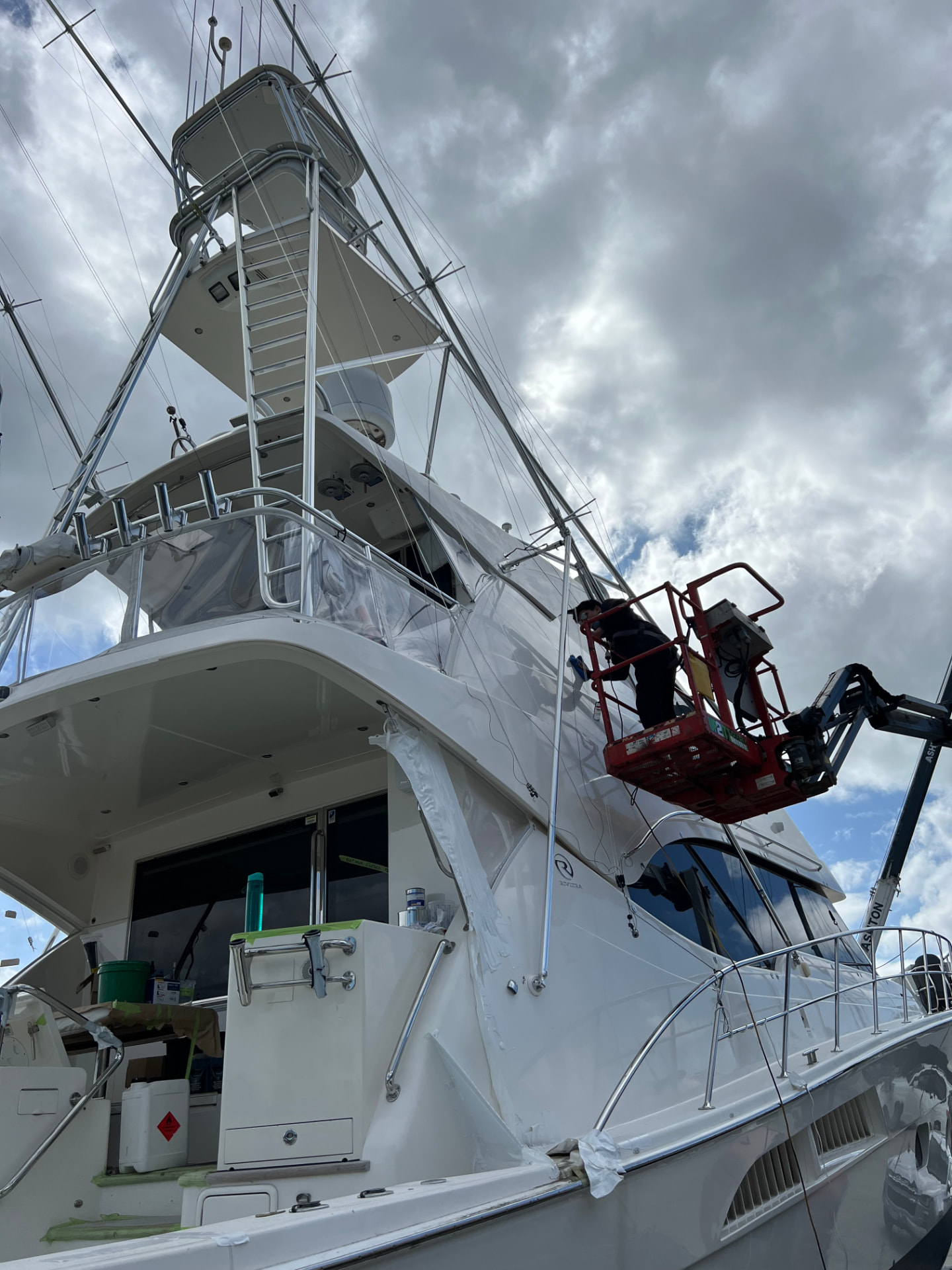 Technician on a cherry picker detailing the flybridge of a sportfisher