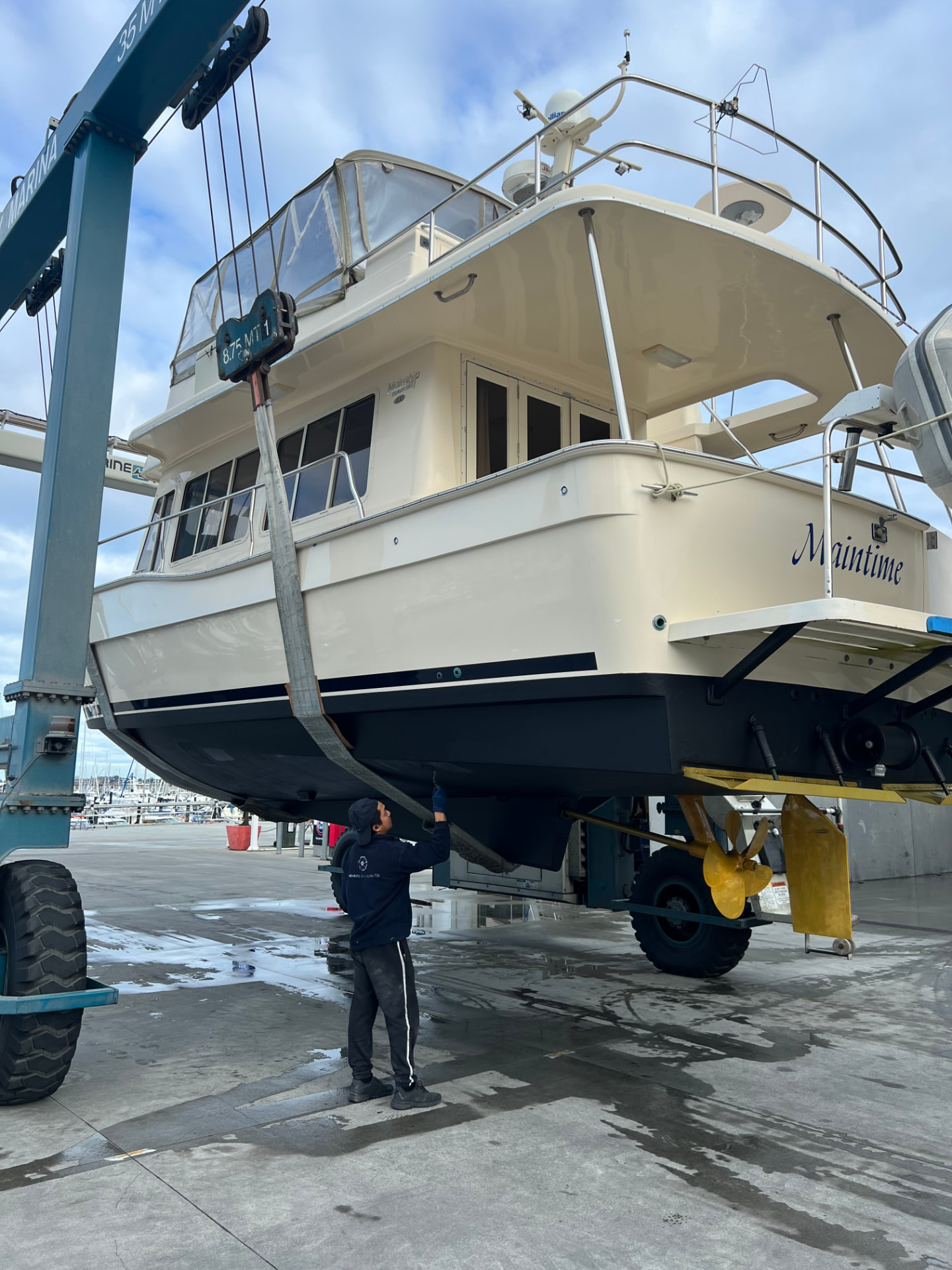 Boat lifted in a travel lift during a haul-out, with antifoul being touched up